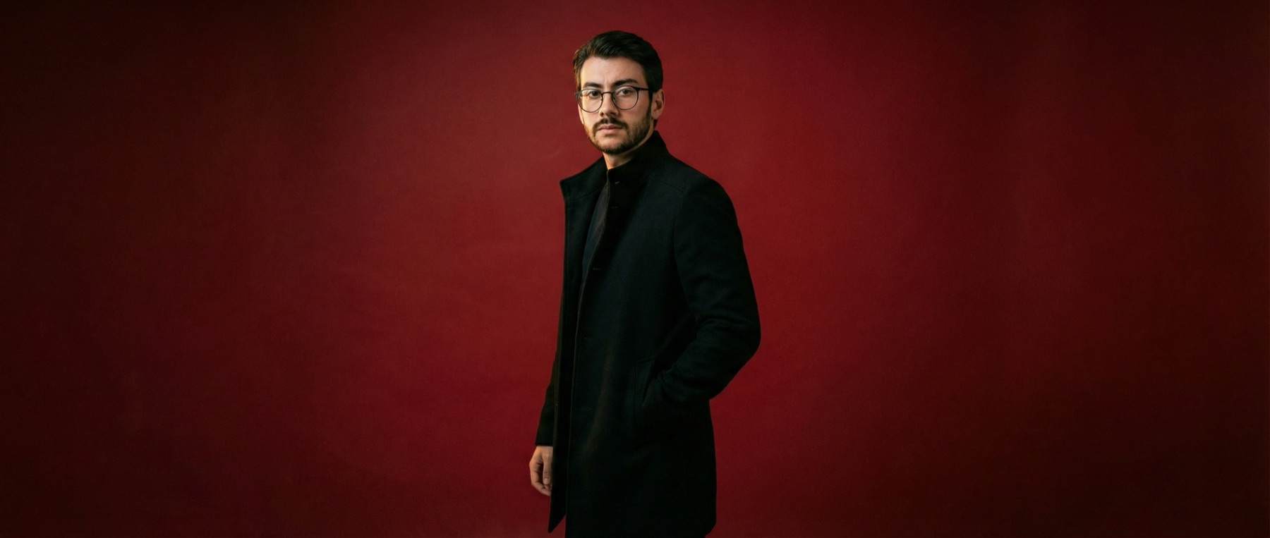 Victor Jangada de sobretudo preto sobre fundo vermelho